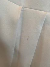 Load image into Gallery viewer, Close up of a small pull in one of the pleats of a size 16 Jamie Wei Huang white asymmetrical hem midi dress with pleated skirt, pocket details, and faux leather straps.
