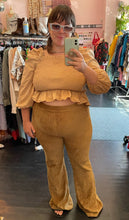 Load image into Gallery viewer, Full-body front view of a size XL Amazon The Drop neutral tone tan smocked long puff sleeve crop top with ruffle hem styled with dark yellow corduroy pants and gray sunnies on a size 14/16 model.
