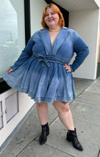 Load image into Gallery viewer, Full-body front view of a size 3 Fashion to Figure x Patrick Starrr lightwash to mediumwash ombré denim belted mini dress with collar and hook-and-eye bust detail styled with black boots on a size 22/24 model.

