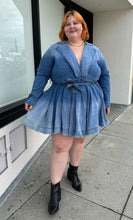 Load image into Gallery viewer, Additional full-body front view of a size 3 Fashion to Figure x Patrick Starrr lightwash to mediumwash ombré denim belted mini dress with collar and hook-and-eye bust detail styled with black boots on a size 22/24 model.
