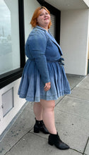 Load image into Gallery viewer, Full-body side view of a size 3 Fashion to Figure x Patrick Starrr lightwash to mediumwash ombré denim belted mini dress with collar and hook-and-eye bust detail styled with black boots on a size 22/24 model.
