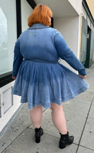 Load image into Gallery viewer, Full-body back view of a size 3 Fashion to Figure x Patrick Starrr lightwash to mediumwash ombré denim belted mini dress with collar and hook-and-eye bust detail styled with black boots on a size 22/24 model.
