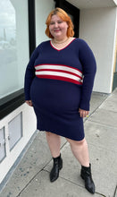Load image into Gallery viewer, Additional full-body front view of a size 22/24 Eloquii x Katie Sturino navy blue ribbed knit sweater dress with red and white varisty stripes and a red and white v-neck stripe styled with black boots on a size 22/24 model. The photo is taken outside in natural lighting.

