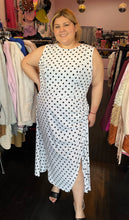 Load image into Gallery viewer, Additional full-body front view showing off the slit of a size 18 ASOS white sleeveless maxi dress with black polka dots and a ruched slit detail at the hem styled with black heels on a size 14/16 model. The photo is taken inside in front of a window, combining natural lighting and overhead lighting.
