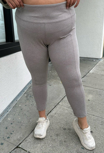 Front view of a pair of size 3X Athleta gray and white mini houndstooth print leggings with zipper pockets styled with white sneakers on a size 18/20 model.