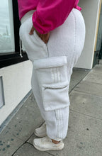 Load image into Gallery viewer, Side view of a size 2X Adidas x Ivy Park white furry drawstring joggers styled with a pink long sleeve tee and white sneakers on a size 18/20 model.

