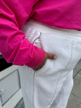 Load image into Gallery viewer, Close up view of the zipper pocket of a size 2X Adidas x Ivy Park white furry drawstring joggers styled with a pink long sleeve tee on a size 18/20 model.
