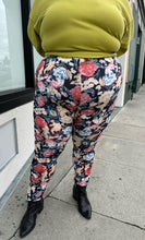 Load image into Gallery viewer, Front view of a pair of size 3X Miss Look muted multicolor floral leggings styled with a chartreuse crewneck and black boots on a size 22/24 model.
