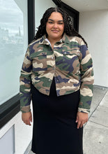 Load image into Gallery viewer, Front view of a size 2X Forever 21 green camo denim jacket with snap closure buttons styled closed over a black dress on a size 18/20 model.
