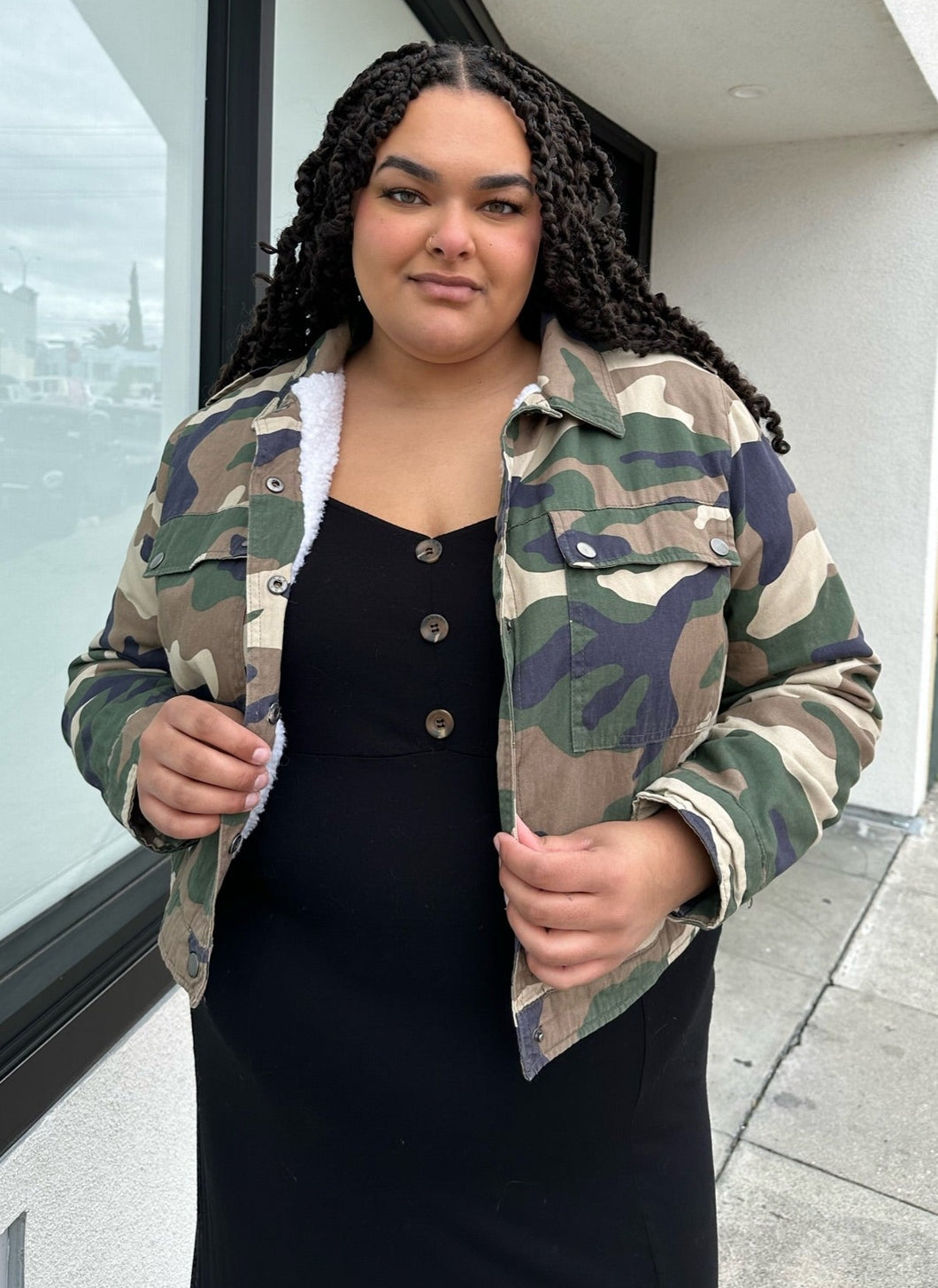 Front view of a size 2X Forever 21 green camo denim jacket with snap closure buttons styled open over a black dress on a size 18/20 model.