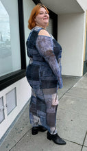 Load image into Gallery viewer, Full-body side view of size 22 Pretty Little Thing denim patchwork pattern mesh bodycon maxi dress with cold shoulders and sheer sleeves styled with black boots on a size 22/24 model.
