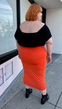 Load image into Gallery viewer, Full-body back view of a size 3X Fashion Nova bright orange bodycon maxi skirt styled with a black off-shoulder blouse and black pointy boots on a size 22/24 model.
