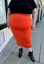 Load image into Gallery viewer, Front view of a size 3X Fashion Nova bright orange bodycon maxi skirt styled with a black off-shoulder blouse and black pointy boots on a size 22/24 model.
