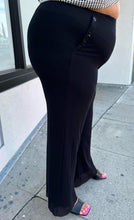Load image into Gallery viewer, Side view of a pair of size XXL Fuzzi via 11 Honoré black trousers with button-studded pockets styled with black heels on a size 18/20 model.

