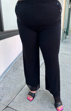 Load image into Gallery viewer, Front view of a pair of size XXL Fuzzi via 11 Honoré black trousers with button-studded pockets styled with black heels on a size 18/20 model.
