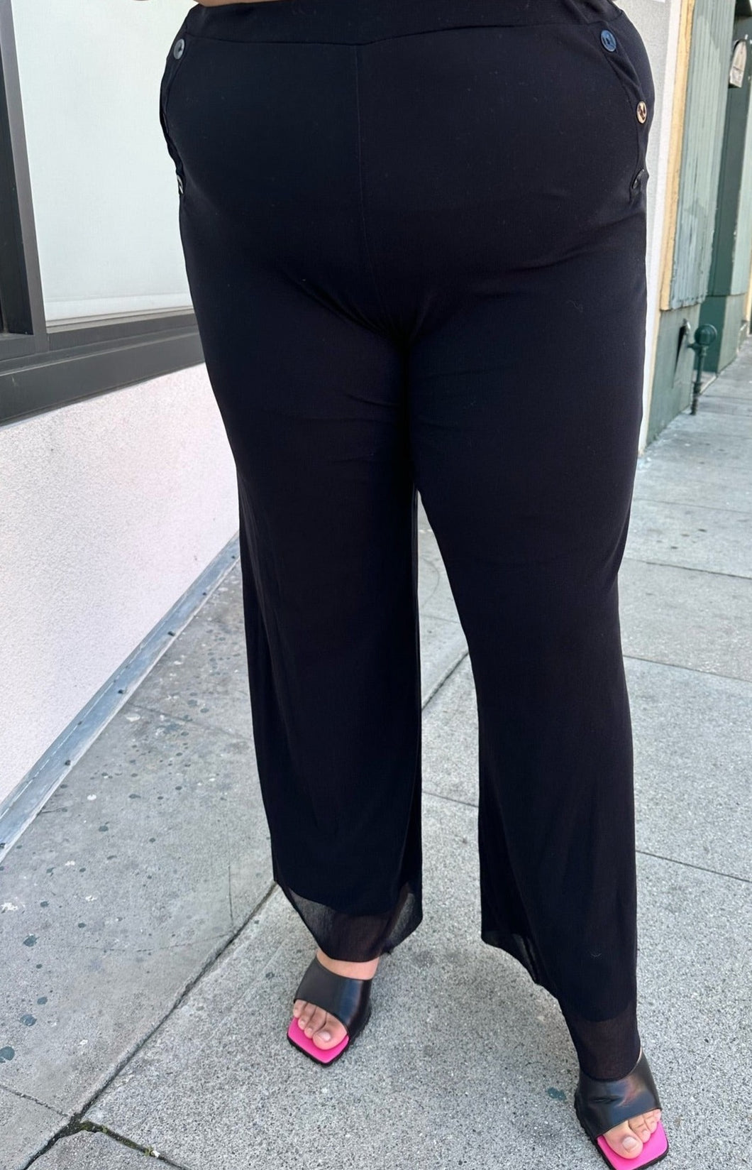 Front view of a pair of size XXL Fuzzi via 11 Honoré black trousers with button-studded pockets styled with black heels on a size 18/20 model.
