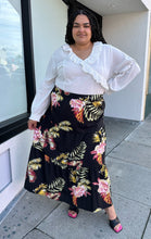 Load image into Gallery viewer, Full-body front view of a size 4X SHEIN black tiered maxi skirt with pink, yellow, and green tropical floral pattern maxi skirt styled with a white blouse and black heels on a size 18/20 model.
