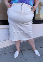 Load image into Gallery viewer, Front view of a size L Universal Standard white deconstructed denim midi skirt styled with a blue and purple tie dye tee and white slides on a size 22/24 model.
