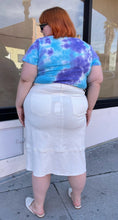 Load image into Gallery viewer, Full-body back view of a size L Universal Standard white deconstructed denim midi skirt styled with a blue and purple tie dye tee and white slides on a size 22/24 model.
