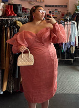 Load image into Gallery viewer, Additional front view of a size 24 ASOS peachy pink lace sheath dress with a corset-style bodice and oversized ruffle bust and sleeves with puff sleeves on a size 22 model. The photo is taken inside under overhead lighting.
