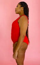 Load image into Gallery viewer, Side view of a size XL Cupshe vibrant red strappy one piece swimsuit with a tortoiseshell ring detail on a size 14 model.
