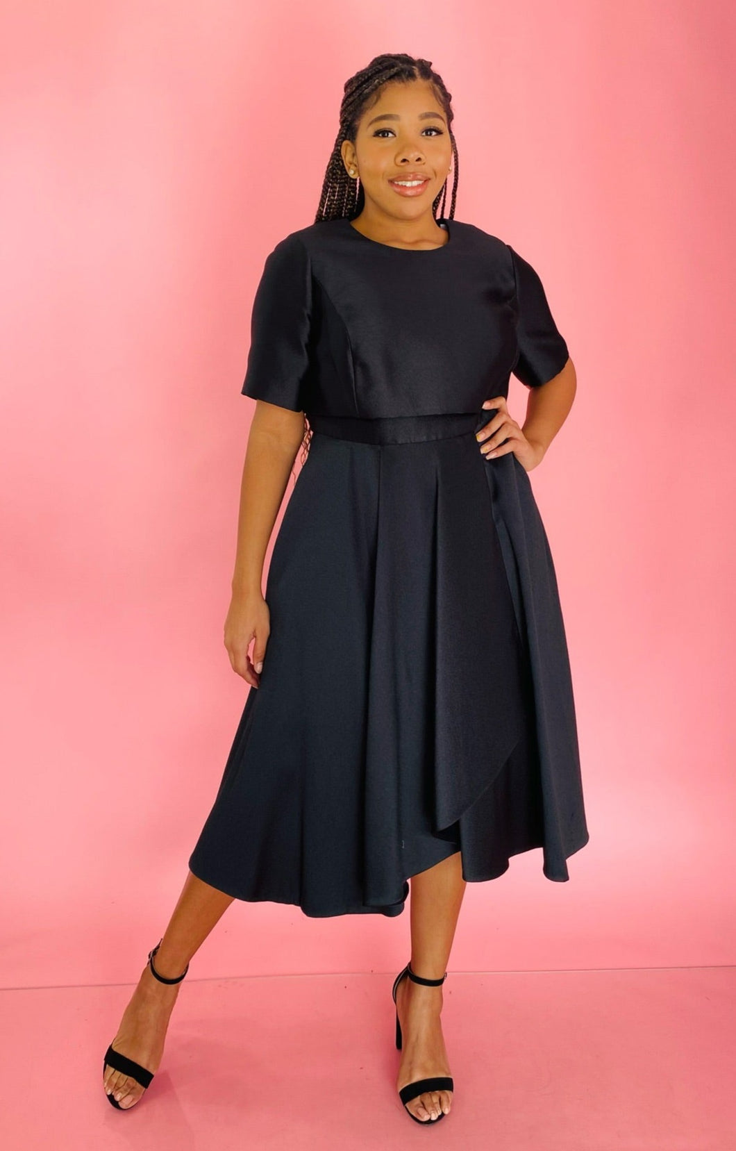 Full-body front view of a size 14 Jason Wu for 11HONORÉ black a-line midi dress with a subtle high-low draping styled with black heels on a size 14 model.