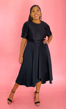 Load image into Gallery viewer, Additional full-body front view of a size 14 Jason Wu for 11HONORÉ black a-line midi dress with a subtle high-low draping styled with black heels on a size 14 model.
