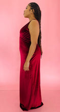 Load image into Gallery viewer, Full-body side view of a size 12/14 Melissa Mercedes deep red velvet floor-length gown with deep v-neck  and tie details at the back on a size 14 model.
