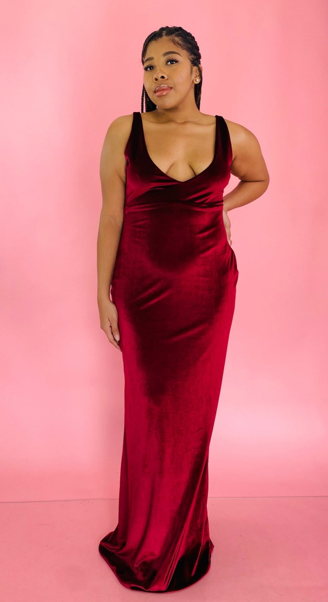Full-body front view of a size 12/14 Melissa Mercedes deep red velvet floor-length gown with deep v-neck  and tie details at the back on a size 14 model.
