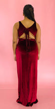Load image into Gallery viewer, Full-body back view of a size 12/14 Melissa Mercedes deep red velvet floor-length gown with deep v-neck  and tie details at the back on a size 14 model.
