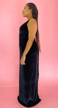 Load image into Gallery viewer, Full-body side view of a size 12/14 Melissa Mercedes black velvet floor-length gown with deep v-neck and tie details at the back on a size 14 model.
