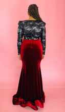 Load image into Gallery viewer, Full-body back view of a size 12/14 deep red velvet high-neck floor-length gown with black and silver sequin sleeves and back, shoulder pad details, and a train on a size 14 model.
