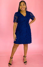 Load image into Gallery viewer, Full-body front view of a size 14 Adrianna Papell navy blue midi dress with floral appliques and sheer mesh sleeves styled with black strappy heels on a size 14 model.
