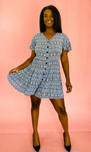 Load image into Gallery viewer, Full-body front view of a size L Andrea brand vintage sky blue, white, and black geometric print mini dress with black buttons up the front styled with black pumps on a size 10/12 model.
