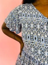 Load image into Gallery viewer, Close up of the flutter sleeve detail on this size L Andrea brand vintage sky blue, white, and black geometric print mini dress with black buttons on a size 10/12 model.
