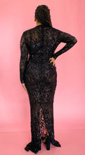 Load image into Gallery viewer, Full-body back view of a size 12/14 Melissa Mercedes black body-hugging floor-length gown with intricate mesh, bead, and sequin work all throughout and a slit at the back on a size 14 model.
