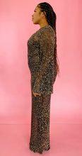 Load image into Gallery viewer, Full-body side view of a size 12/14 Melissa Mercedes sheer brown floor-length gown with gold sequin all-over pattern, wide bell sleeves, and back slit on a size 14 model.
