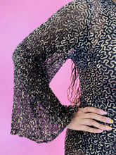 Load image into Gallery viewer, Close up detail shot of the gold sequin all-over pattern of this size 12/14 Melissa Mercedes sheer brown full-length gown with bell sleeves.

