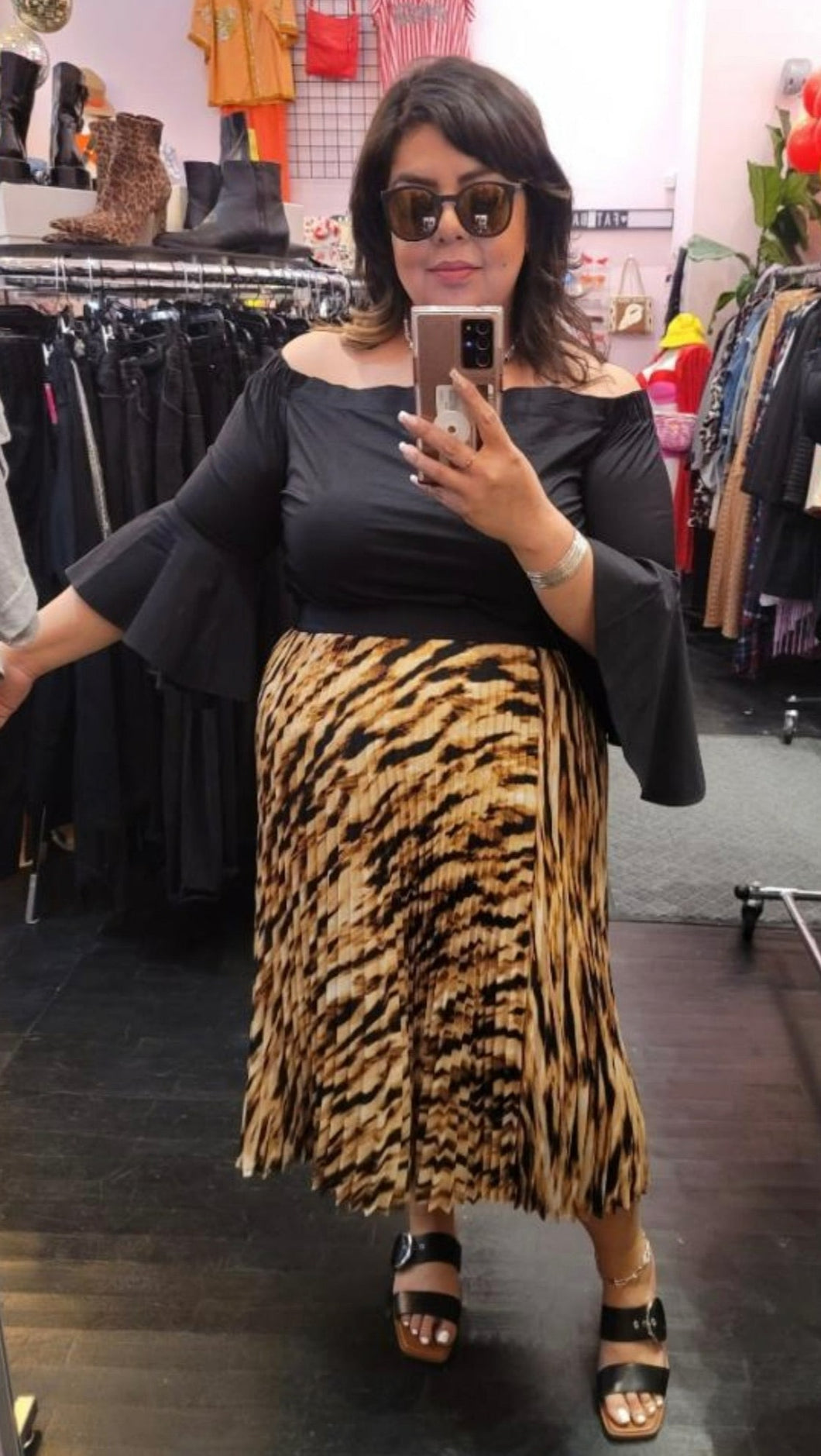 Full-body front view of a size 2X Leith (Anthropologie) brown and black zebra stripe plisse pleated maxi skirt styled with a black bell sleeve top on a size 14/16 model.