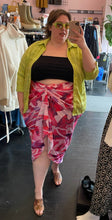 Load image into Gallery viewer, Additional front view of a size 24 Pretty Little Thing hot pink, light pink, purple, and white abstract watercolor patterned gathered midi skirt styled with a black tank and acid green button-up top on a size 24 model.
