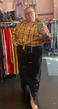 Load image into Gallery viewer, Full-body front view of a size 3X Walk of Shame brand yellow, red, and white snap-button closure blouse with drawstring neckline and asymmetrical side details styled with the top knotted over a black denim maxi skirt on a size 24 model.
