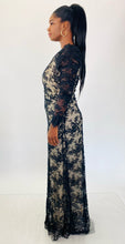 Load image into Gallery viewer, Full-body side view of this size 16 Monique Lhuillier for 11Honoré one-shoulder cream gown with sheer black lace overlay and high side slit styled with maroon strappy heels on a size 12 model.
