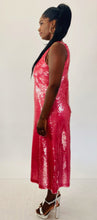 Load image into Gallery viewer, Full-body side view of a size 14 Dima Ayaad grapefruit pink colored v-neck gown with big sequins all throughout styled with shiny silver block heels on a size 12 model. The photo is taken inside under studio lighting.
