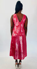 Load image into Gallery viewer, Full-body back view of a size 14 Dima Ayaad grapefruit pink colored v-neck gown with big sequins all throughout styled with shiny silver block heels on a size 12 model. The photo is taken inside under studio lighting.
