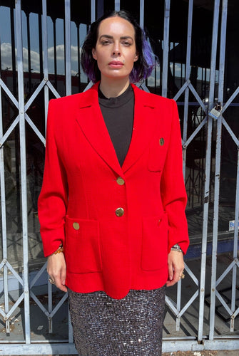 Front view of a size 14 (fits like 12) Yves Saint Laurent vintage red blazer with large gold buttons and pocket details styled over a black blouse and silver sequin pencil skirt on a size 10 model. The photo is taken outside in natural lighting.