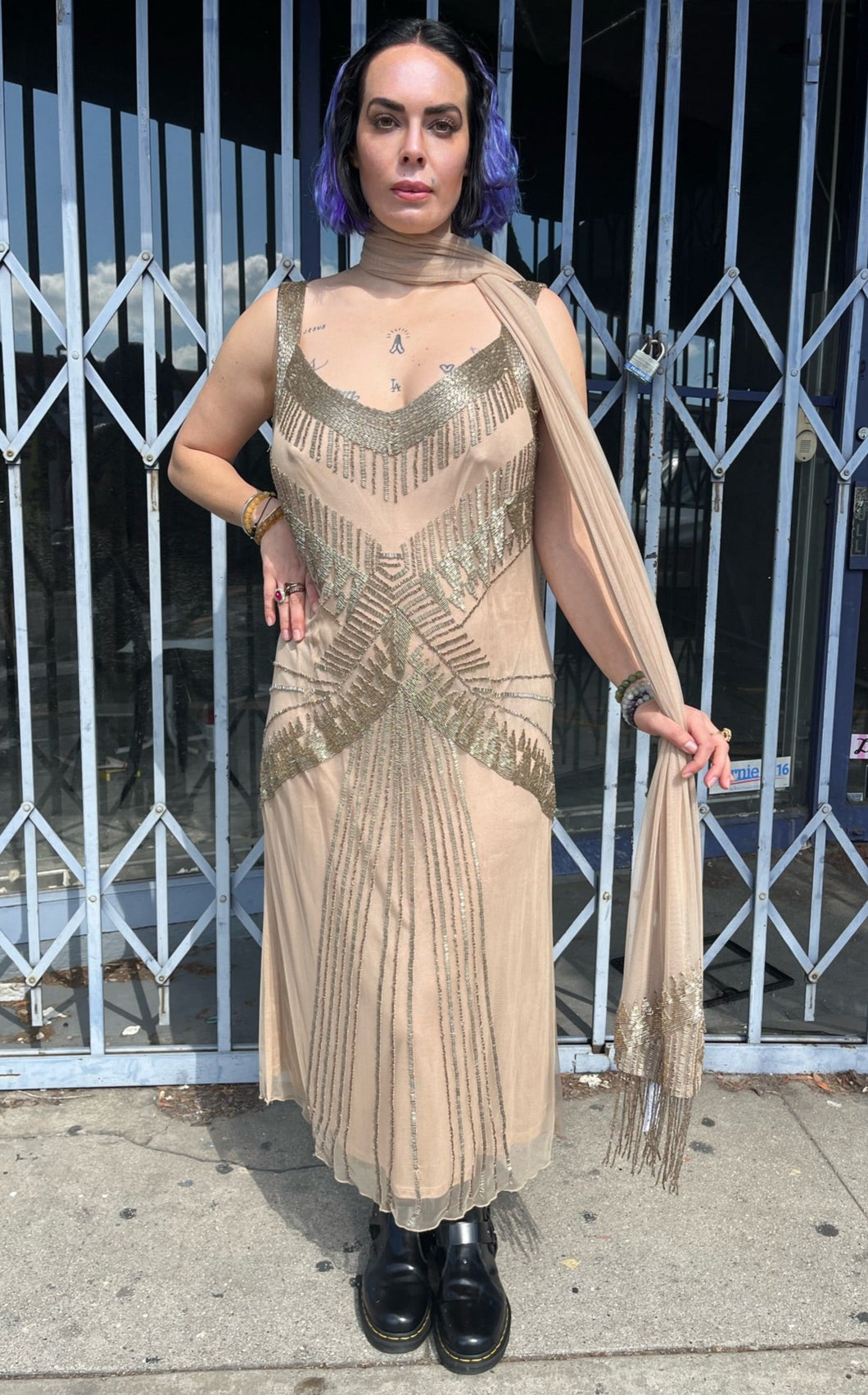 Full-body front view of a size 16 (fits like 14) Marina Rinaldi cream colored gown with intricate champagne-beaded mesh overlay and shawl-scarf styled with the shawl tied as a scarf and black boots on a size 10 model.