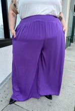 Load image into Gallery viewer, Front view of a pair of size 28 Eloquii purple lightweight wide leg pants with elastic waistband styled with a white ruffled tank and black boots on a size 22/24 model.
