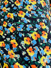 Load image into Gallery viewer, Close up with of the mini yellow, blue, green, and orange floral pattern on this size 26 Jason Wu x Eloquii ruffled wrap dress.
