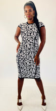 Load image into Gallery viewer, Full-body front view of this size M Michael Kors black and white textured floral sheath midi dress with cap sleeves styled with strappy white heels on a size 12 model.
