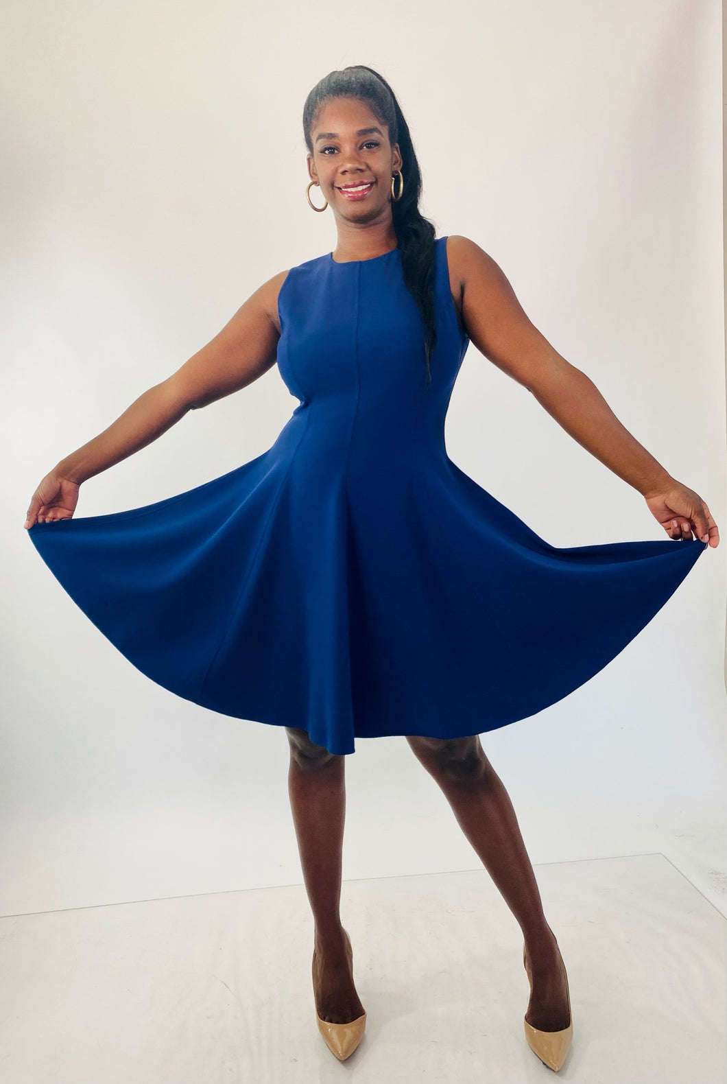 Full-body front view of a size 16 Michael Kors navy blue high-neck a-line dress with circle skirt styled with tan patent leather pumps on a size 12 model.